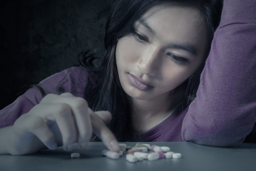 woman staring at pills on table