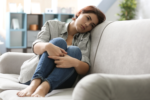 woman laying on couch looking depressed