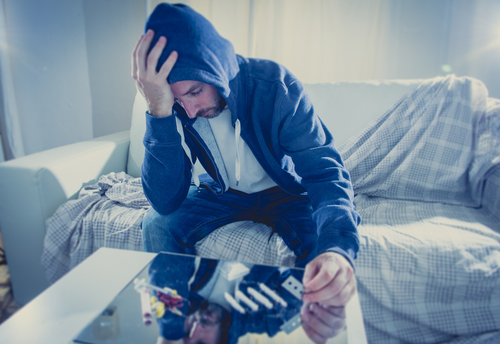 man sitting on couch with cocaine lines on table, learning how to quit cocaine