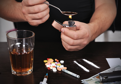 person using meth with alcohol and pills on the table