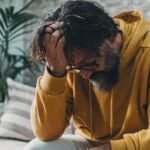 Distressed man with hand on head after asking can xanax cause depression.